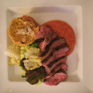 Grilled NY strip  on roasted red pepper coulis paired with cous cous and Australian finger lime caviar with Thai basil-lime vinaigrette dressed greens